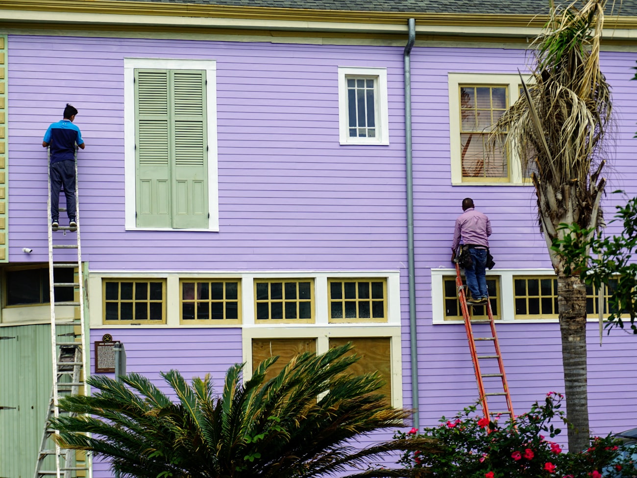 Painters on ladders repainting a timber house exterior