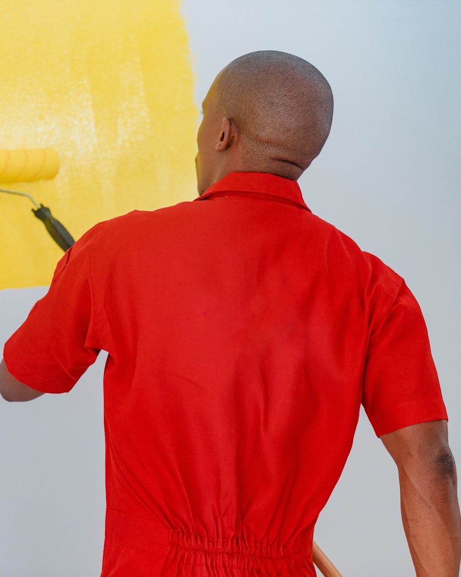 Painter in red overalls applying bold yellow paint