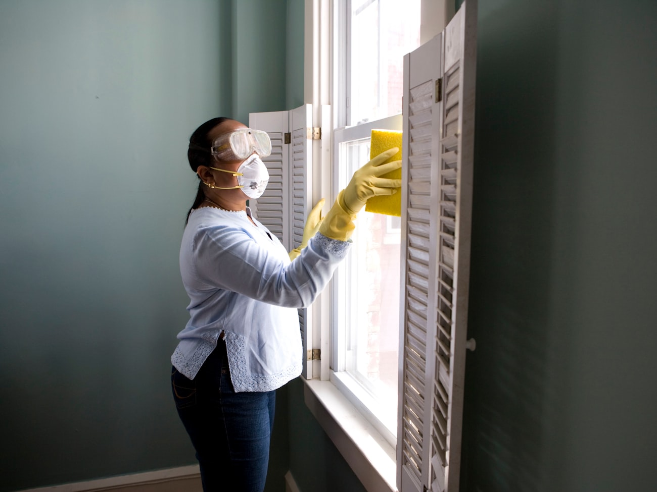 Painter preparing and masking a window before painting